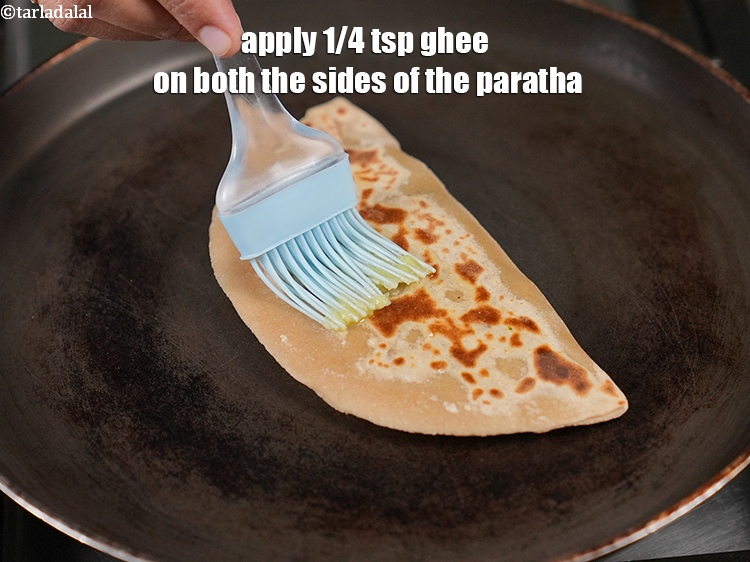Step 30 – Apply 1/4 tsp <a href="https://www.tarladalal.com/glossary-ghee-245i">ghee</a> on both the sides of the paratha.