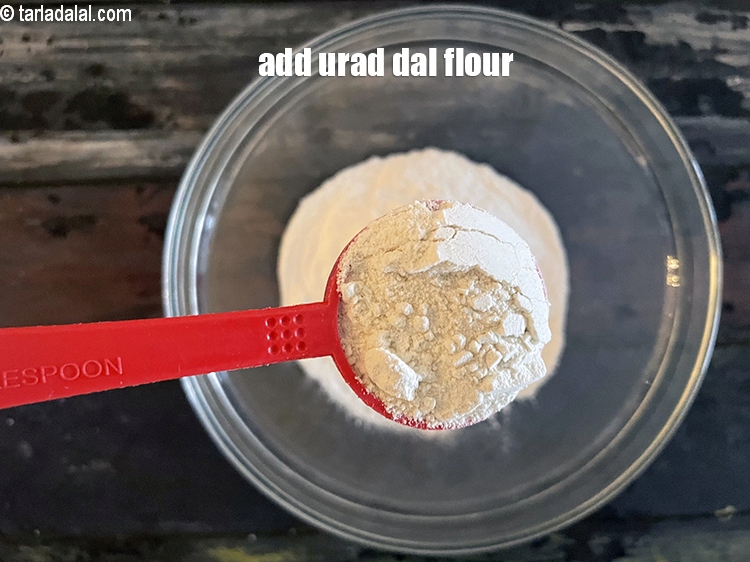 Step 7 – Add 2&nbsp;tbsp&nbsp;<a href="glossary-urad-dal-flour-split-black-lentil-flour-urad-dal-ka-atta-1036i">urad dal (split black lentil) flour</a>.