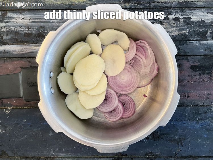 स्टेप 6 – १/२ कप&nbsp;पतले&nbsp;<a href=""https://www.tarladalal.com/glossary-potato-slices-hindi-2445i"">आलू के स्लाइस</a>&nbsp;डालें । अगर आप वजन घटा …