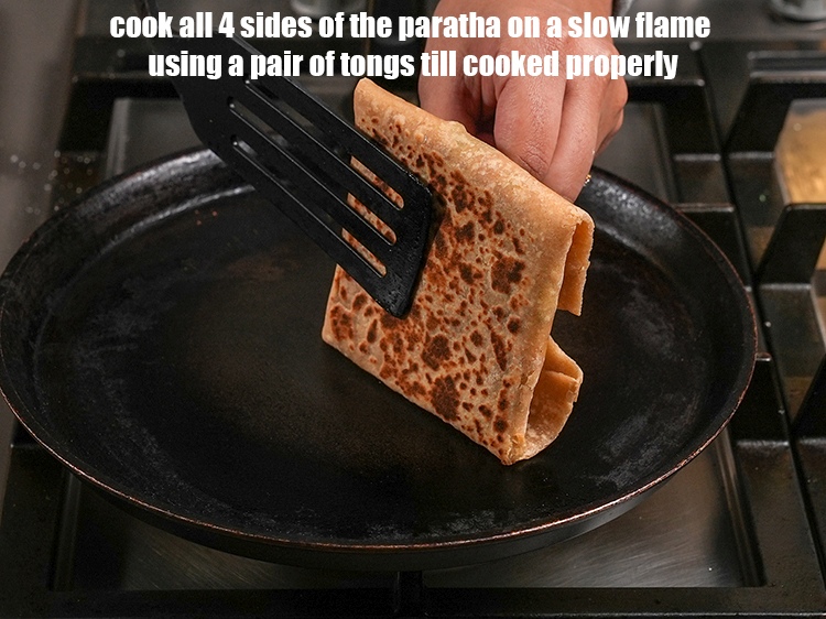 Step 59 – <meta charset="UTF-8" />Cook all 4 sides of the paratha on a slow flame using a …