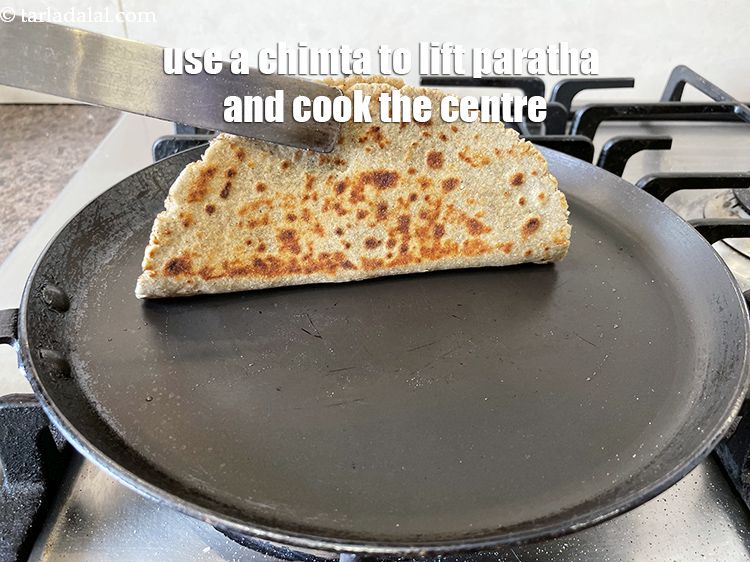 Step 35 – Remember to use a chimta and lift the paratha to cook the centre of the …