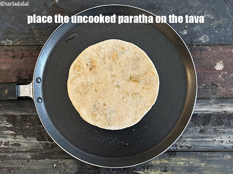 Step 44 – <meta charset="UTF-8" />Place the uncooked paratha on the tava.&nbsp;