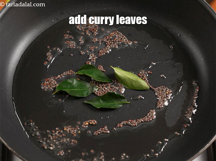 Step 5 – When the seeds crackle, add 6 curry leaves.