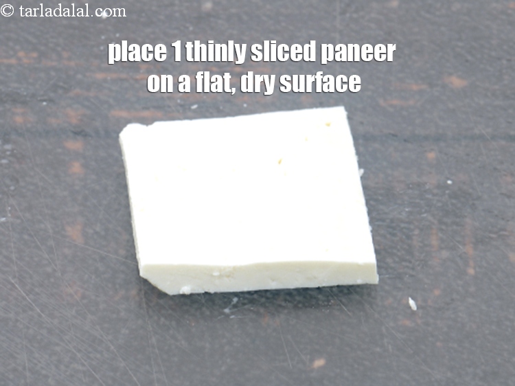 Step 16 – Place 1 thinly&nbsp;<a href="https://www.tarladalal.com/glossary-sliced-paneer-996i">sliced paneer (cottage cheese)</a> on a flat, dry surface.