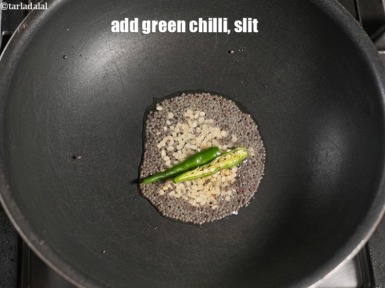 Step 6 – When the seeds crackle, add 1 <a href="https://www.tarladalal.com/glossary-slit-green-chillies-1856i">green chilli , slit</a>.