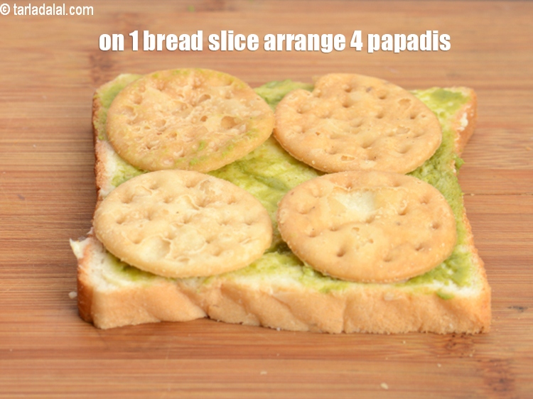 Step 7 – On 1 buttered-chutney bread slice.&nbsp;Arrange 4 <a href="https://www.tarladalal.com/glossary-papdi-chaat-chaat-ki-puri-1999i">papadis</a>.&nbsp;