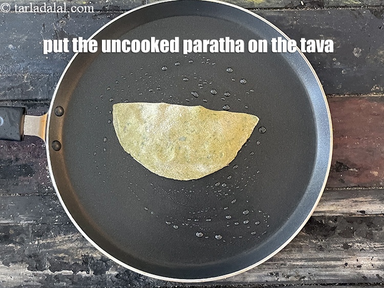 Step 43 – <meta charset="UTF-8" />Put the uncooked paratha on the tava.&nbsp;<br /> &nbsp;