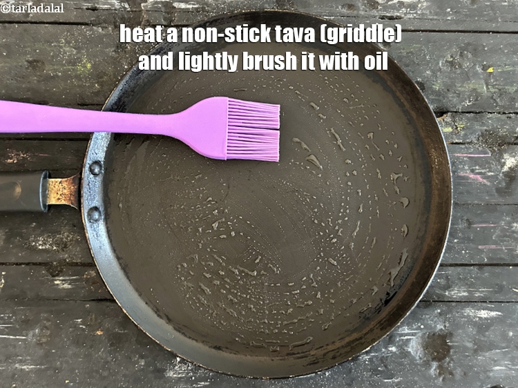 Step 45 – <meta charset="UTF-8" /> Heat a non-stick tava (griddle)&nbsp;and lightly brush it with oil.