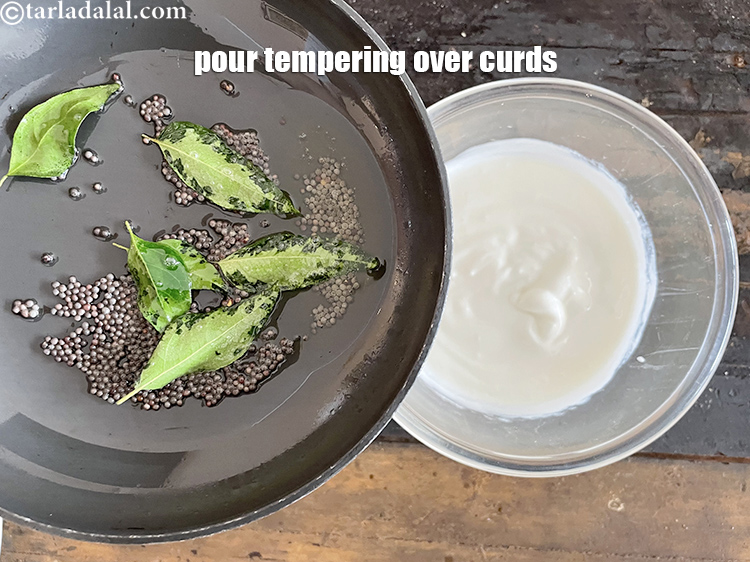 स्टेप 59 – तड़के को दही के ऊपर डालें।