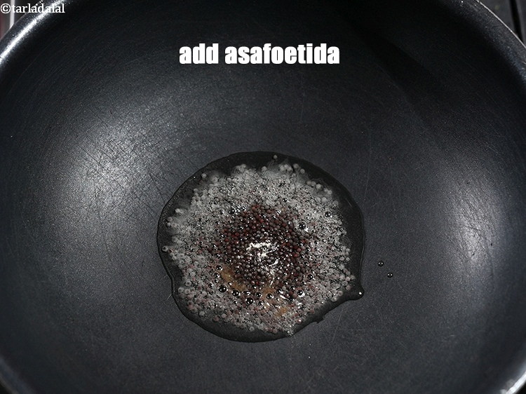 Step 8 – When the seeds crackle, add a pinch of asafoetida.