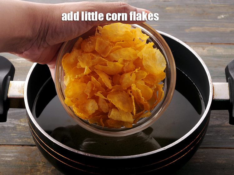 Step 10 – Add little <a href="https://www.tarladalal.com/glossary-corn-flakes-157i#ing_2391" target="_blank">corn flakes</a> at a time so they have space to expand …