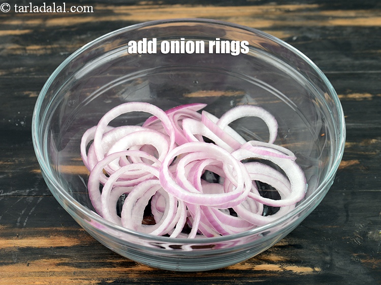 Step 8 – To make lachha onion, in a deep bowl, add 1 &frac12; cups of <a href="https://www.tarladalal.com/glossary-onion-rings-987i">onion …