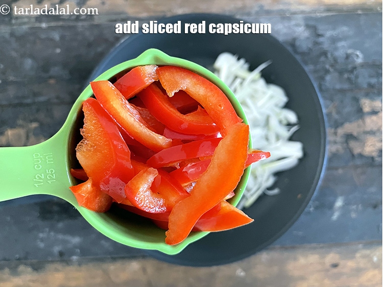 स्टेप 9 – १/२ कप <a href=""https://www.tarladalal.com/glossary-sliced-red-capsicum-hindi-2176i"">स्लाईस्ड लाल शिमला मिर्च</a> डालें।