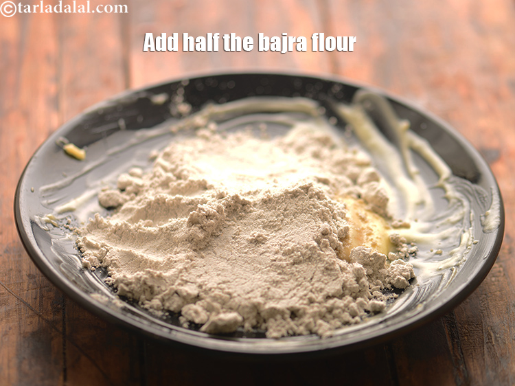 Step 21 – Add half the <a href="https://www.tarladalal.com/glossary-bajra-flour-bajra-ka-atta-bajre-ka-atta-176i">bajra (black millet) flour</a>.