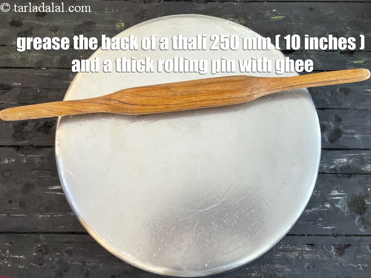 Step 10 – First grease the back of a 250 mm. (10&rdquo;) thali and a thick rolling pin …