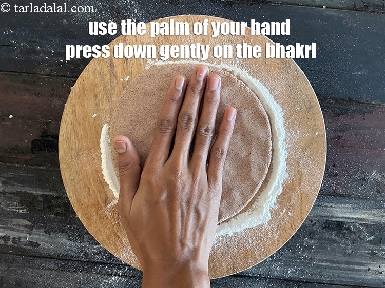 Step 27 – Using the palm of your hand press down gently &nbsp;on the bhakri and roll it …