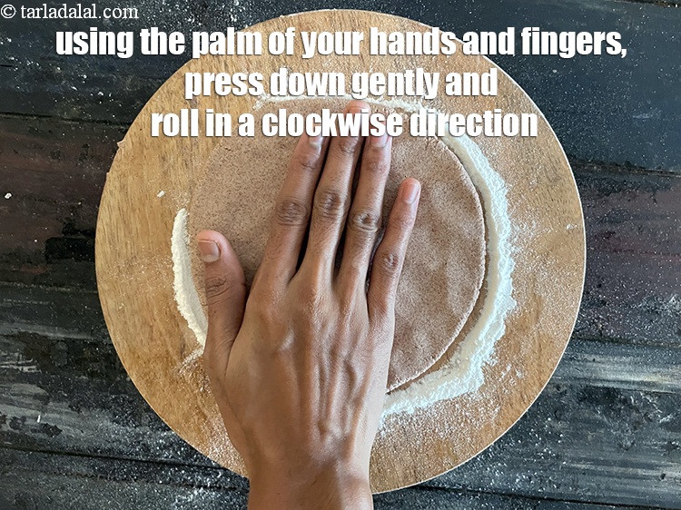 Step 12 – Using the palm of your hand press down gently on the bhakri and roll it …