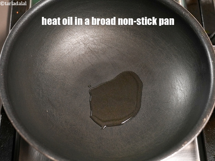 Step 11 – To make <strong>masala karela</strong>, heat 2 tsp oil in a broad non-stick pan.