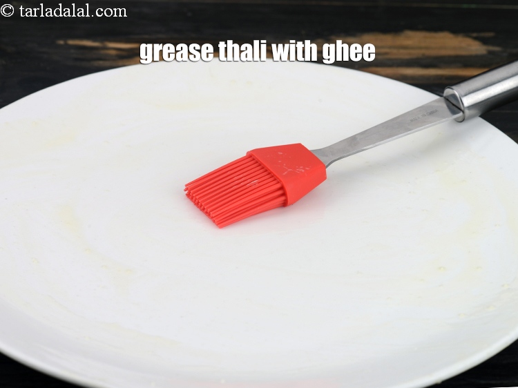 Step 12 – <p>Grease a plate or thai with ghee. &nbsp;</p>