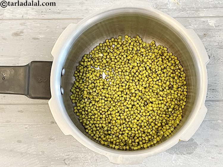 स्टेप 6 – प्रेशर कुकर में भीगे हुए मूंग डालें।