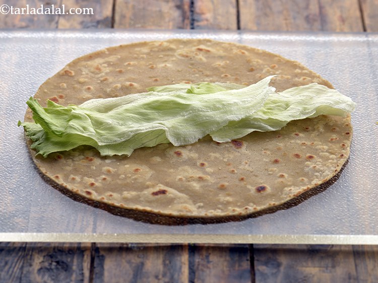 Step 40 – Arrange &frac14; cup of lettuce in a row in the centre of the chapati. A …