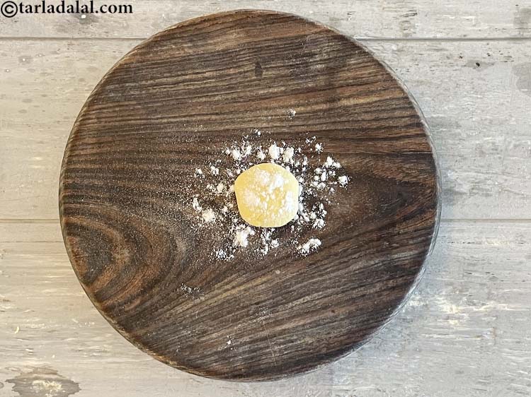 स्टेप 14 – लोई को हथेलियों से चपटा कीजिये, थोड़ा सा मैदा छिड़क …