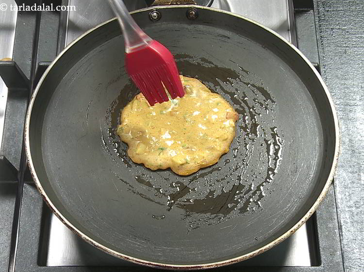 Step 19 – Cook the <strong>thalipeeth</strong> on a medium flame and pour a little oil over it.