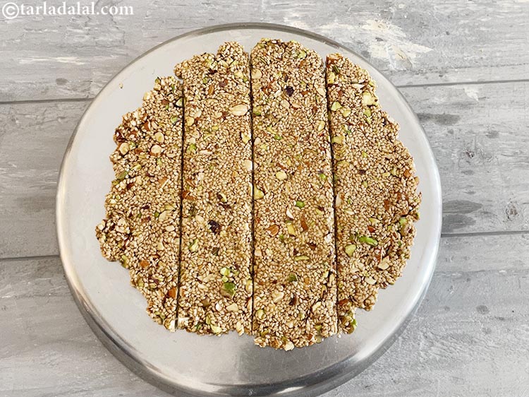 Step 17 – As the chikki is still hot, cut vertical lines accross the chikki. NOTE that the …