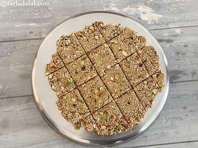 Step 18 – As the chikki&nbsp;is still hot, cut horizontal lines which makes square pieces&nbsp;cut it into 13 …