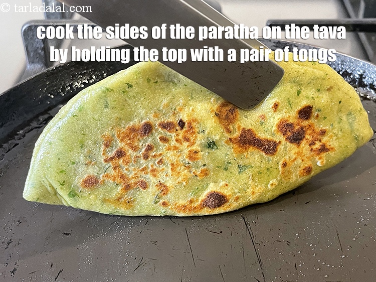 Step 50 – Cook the sides of the paratha on the tava by holding the top with a …