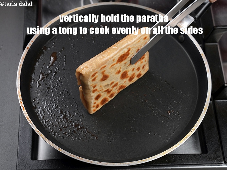 Step 42 – Vertically hold the paratha using a tong to cook evenly on all the sides.
