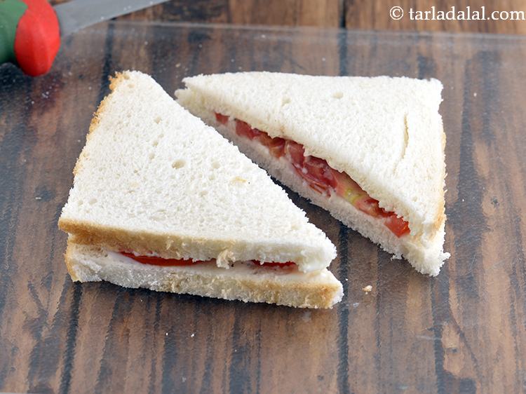 स्टेप 9 – <strong>टोमैटो चीज़ सैंडविच</strong> को २ तिरछे टुकड़ों में काटें।