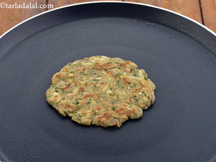 Step 19 – Flip and brush the <strong>Upvaas thalipeeth</strong> with&nbsp;&frac12; tsp more ghee.