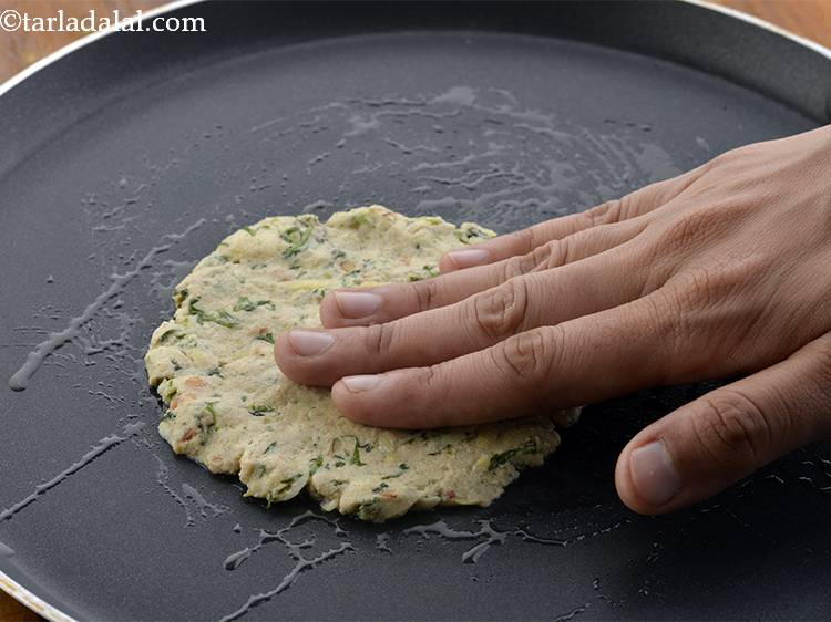 Step 17 – Place a portion of the dough on the <em>tava</em> (griddle) and pat it evenly with …