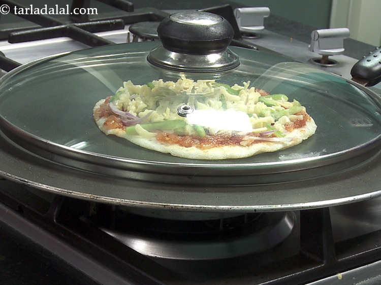 Step 9 – Heat a non-stick tava (griddle), place the uttapam pizza on it and cover with a …