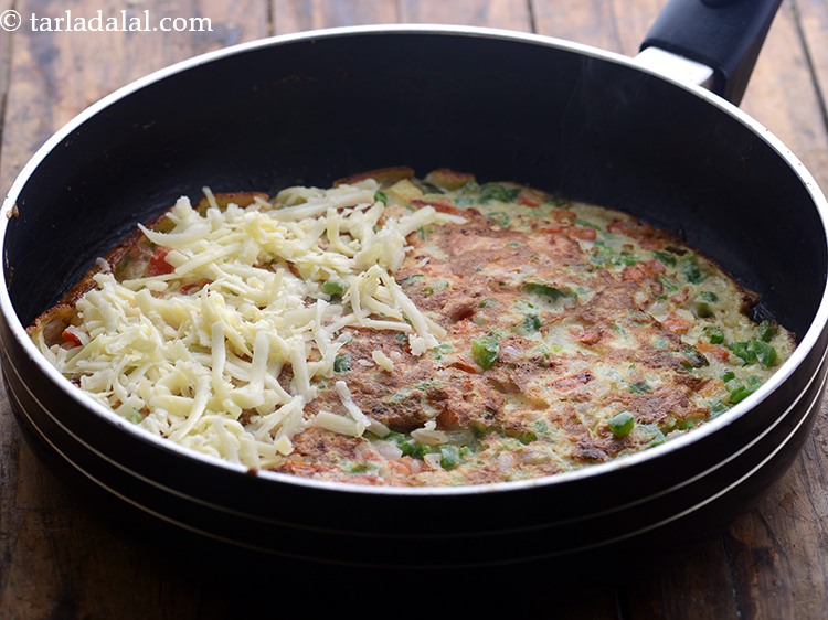 स्टेप 14 – ऑमलेट के आधे भाग में चीज फैलाएं।