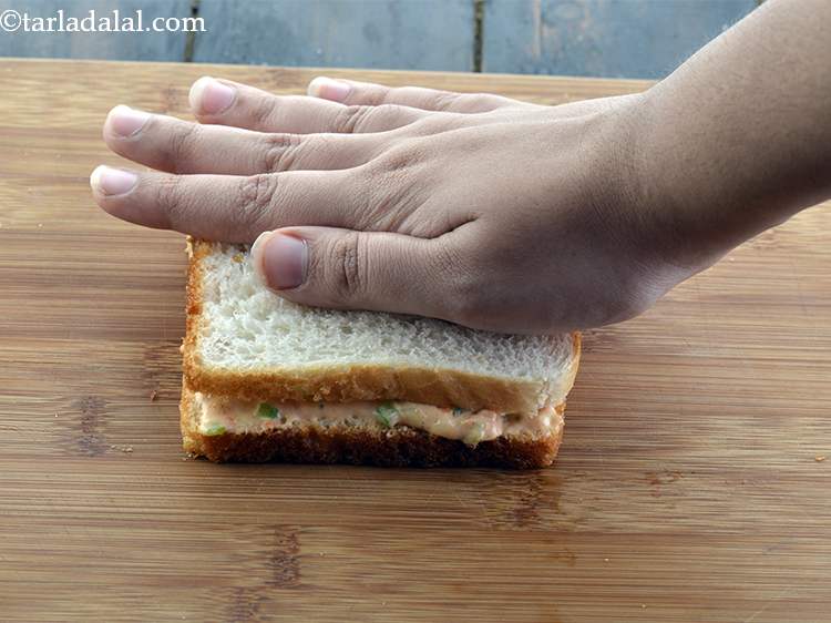 स्टेप 14 – दूसरी हल्का मक्खन चुपडी हुई ब्रेड स्लाइस रखें, जिसमें मक्खन …