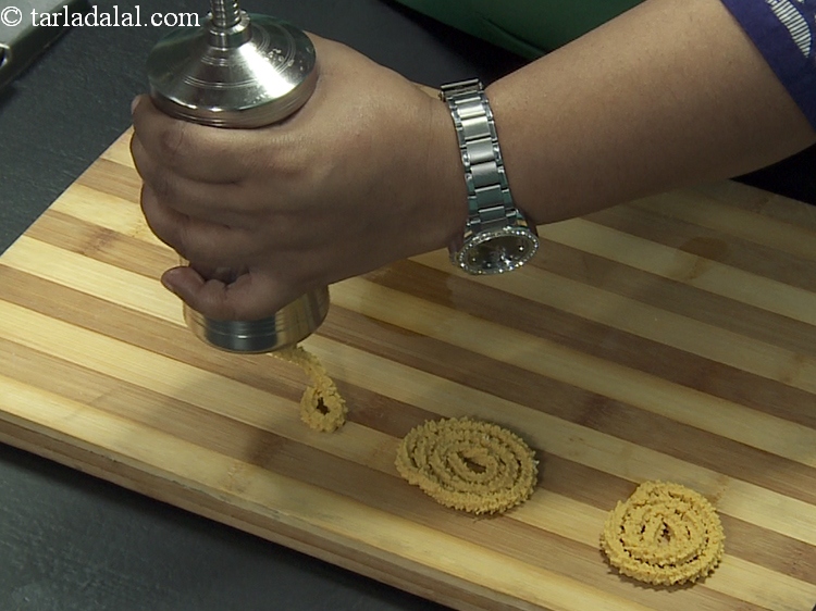 Step 30 – Press out 50 mm. (2&rdquo;) diameter round swirls of chakli onto an inverted flat board …