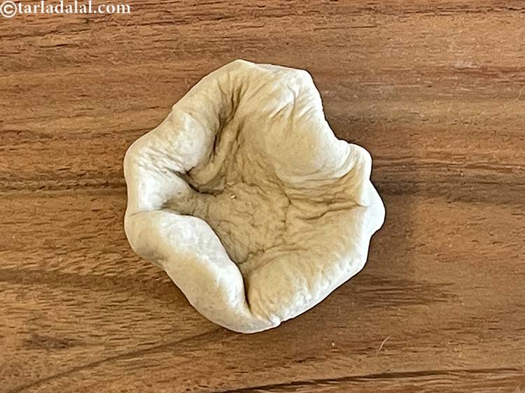 Step 13 – Then squeeze the flat dough with your finger tips to make an open pouch shape.