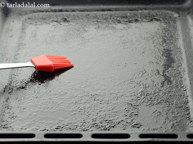 Step 27 – To prepare <strong>atta masala bread rolls</strong>, grease a baking tray with oil and keep aside.