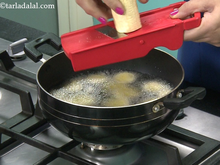 Step 9 – Slice half the raw banana using a slicer directly into the hot oil. We would …