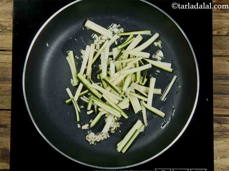 Step 2 – Add the zucchini to the pan. This zucchini is not peeled and has been thinly …