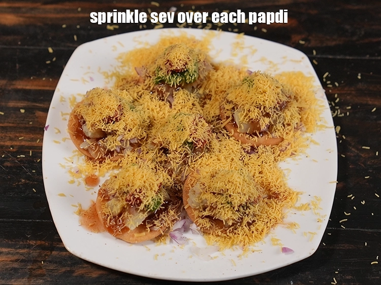 Step 12 – <p><span style="background-color:rgb(255,255,255);color:rgb(0,0,0);">Sprinkle 1½ tsp of sev over each papdi.</span></p>
