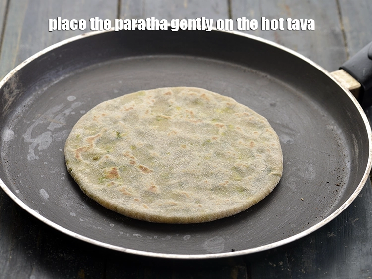 Step 25 – <p>Place the stuffed <strong>aloo methi paratha</strong> gently on the hot tava. Cook one side of …