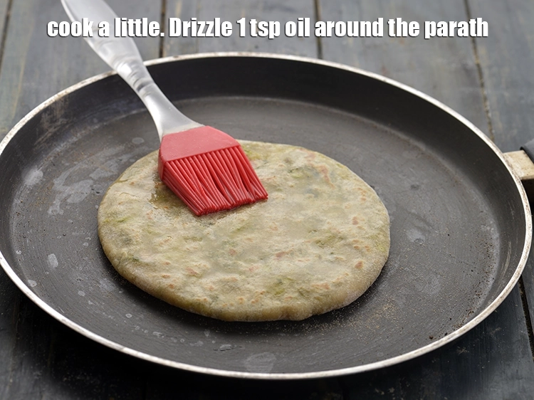 Step 26 – <p>Flip the&nbsp;<strong>Aloo Methi paratha</strong>&nbsp;and cook a little. Drizzle 1 tsp oil around the paratha.</p>