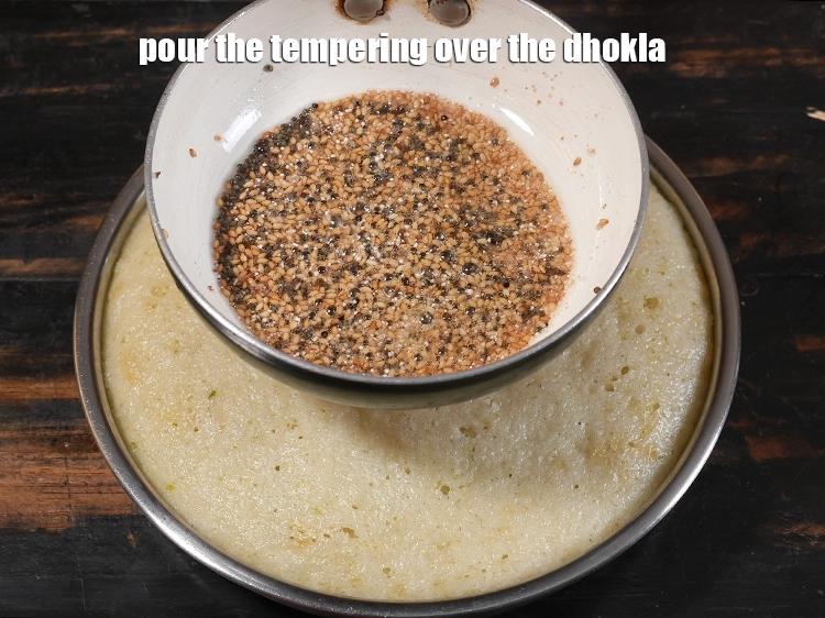 Step 14 – <p><span style="background-color:rgb(255,255,255);color:rgb(0,0,0);">Pour the tempering over the&nbsp;</span><strong>Rava Dhokla ( Suji Dhokla).</strong></p>