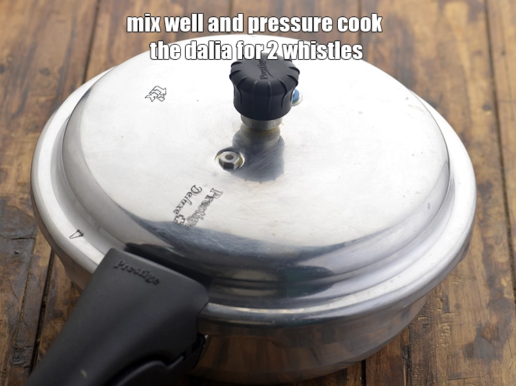 Step 26 – <p><span style="background-color:rgb(255,255,255);color:rgb(0,0,0);">Mix well and pressure cook the dalia for 2 whistles. We only pressure cook …