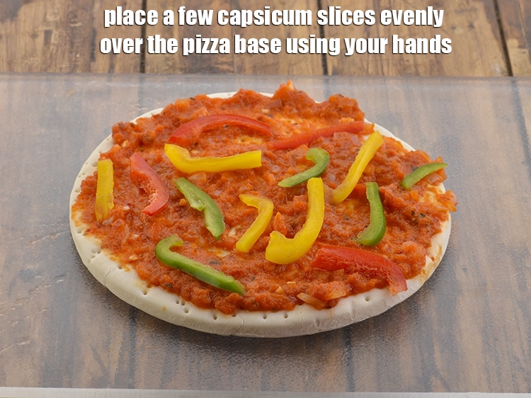 Step 26 – <p>Place a few capsicum slices evenly over the pizza base using your hands.</p>