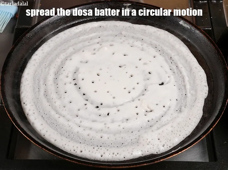 Step 52 – <p>Spread the dosa batter in a circular motion using a ladle to make a 200 …