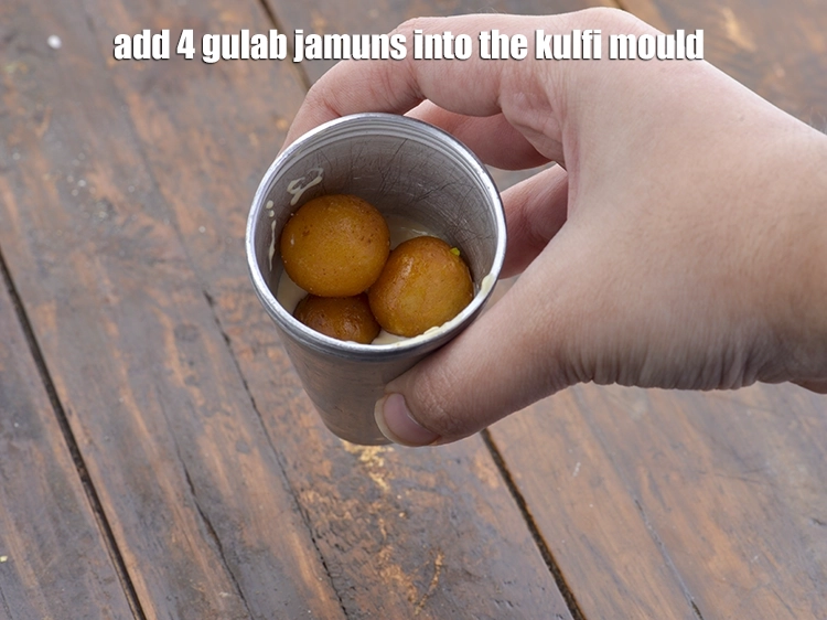 Step 13 – <p><span style="background-color:rgb(255,255,255);color:rgb(0,0,0);">Add 4 </span><a href="https://www.tarladalal.com/gulab-jamun-2854r"><u>gulab jamuns</u></a><span style="background-color:rgb(255,255,255);color:rgb(0,0,0);"> into the kulfi mould.</span></p>